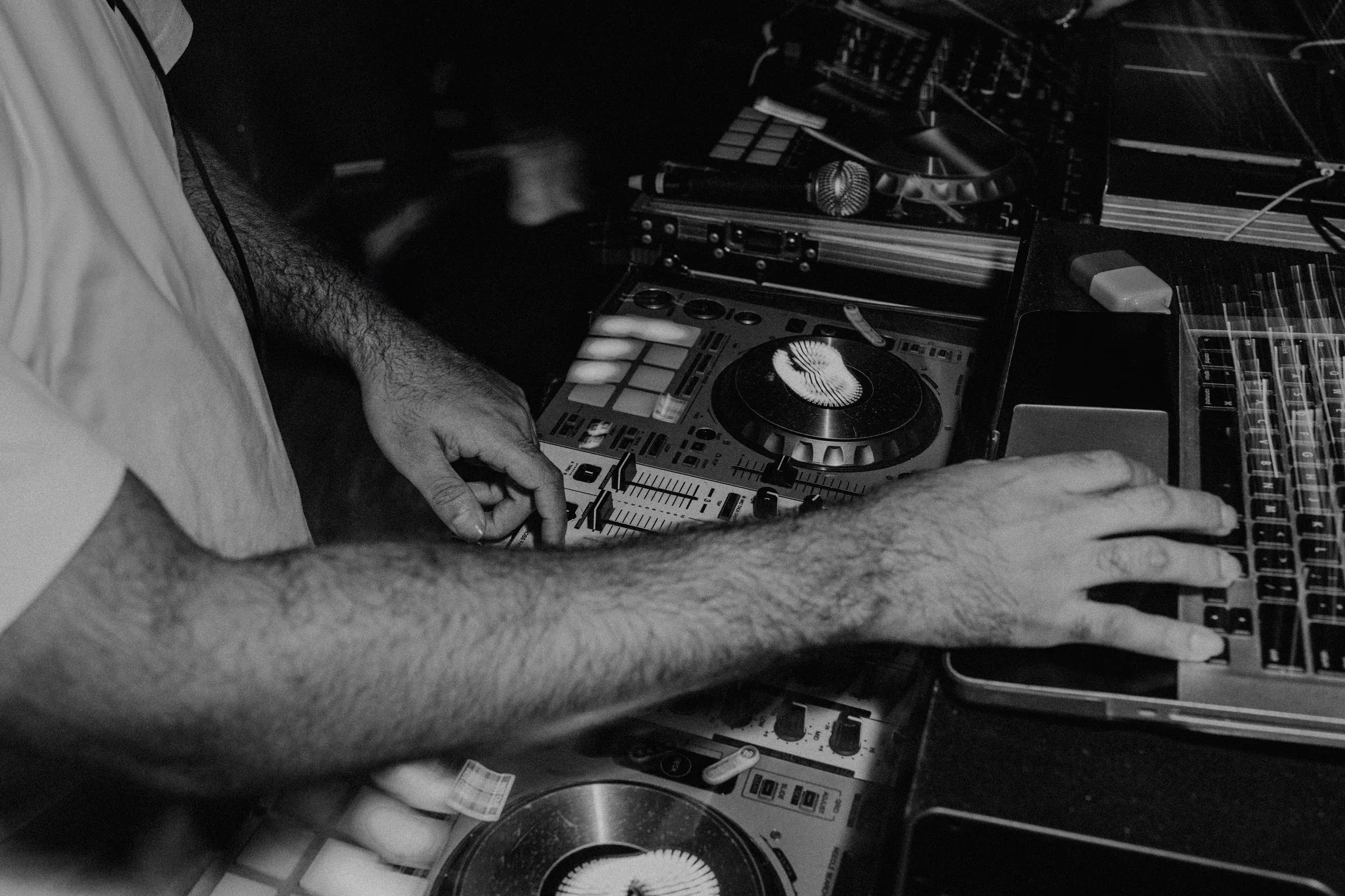 Les mains d'un DJ sur sa console, entre platines et clavier d'ordinateur.