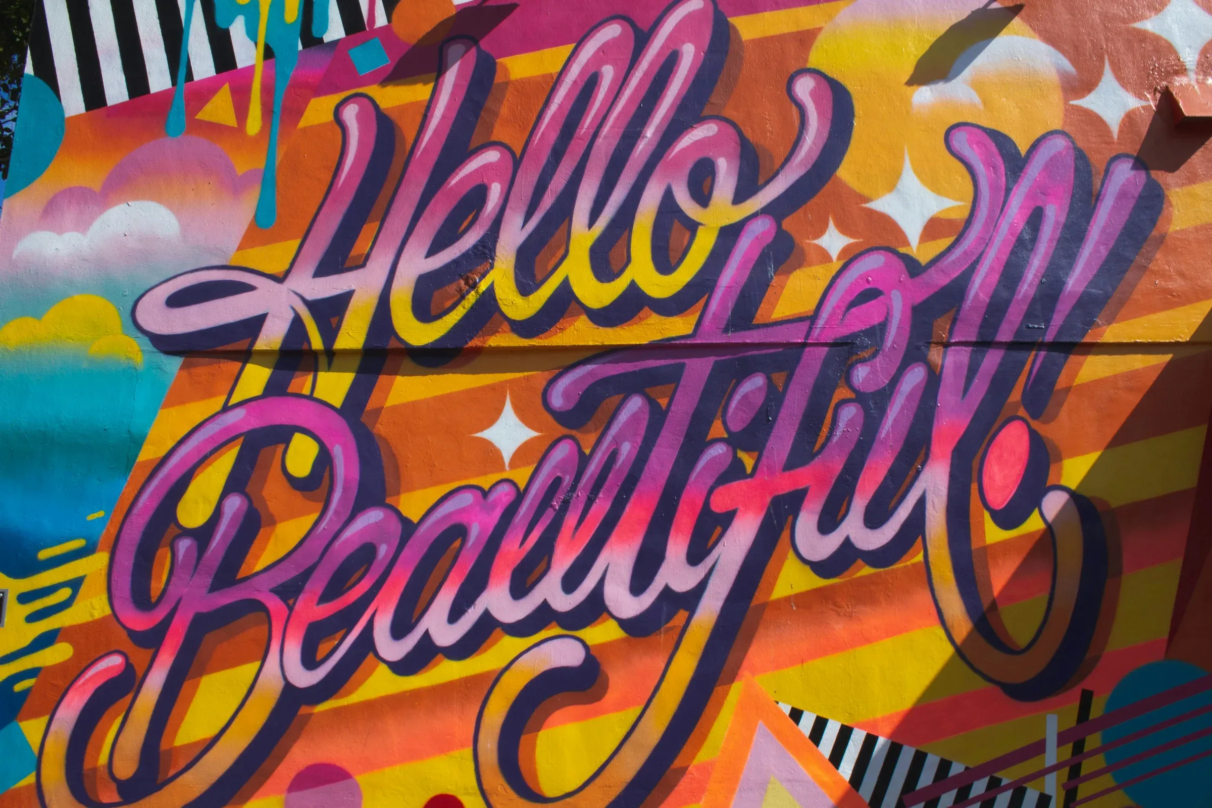 Une fresque murale peinte à la bombe, lettrage en couleurs sur fond rayé.