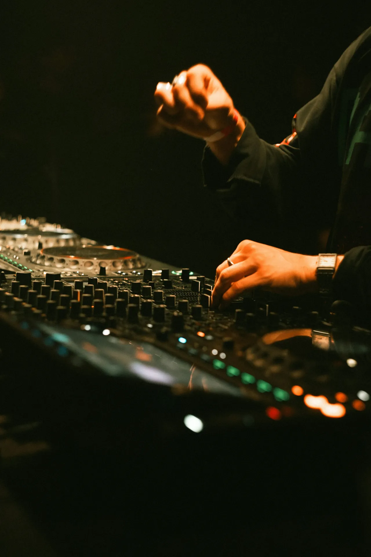 Un DJ aux platines sous les faisceaux de lumière.
